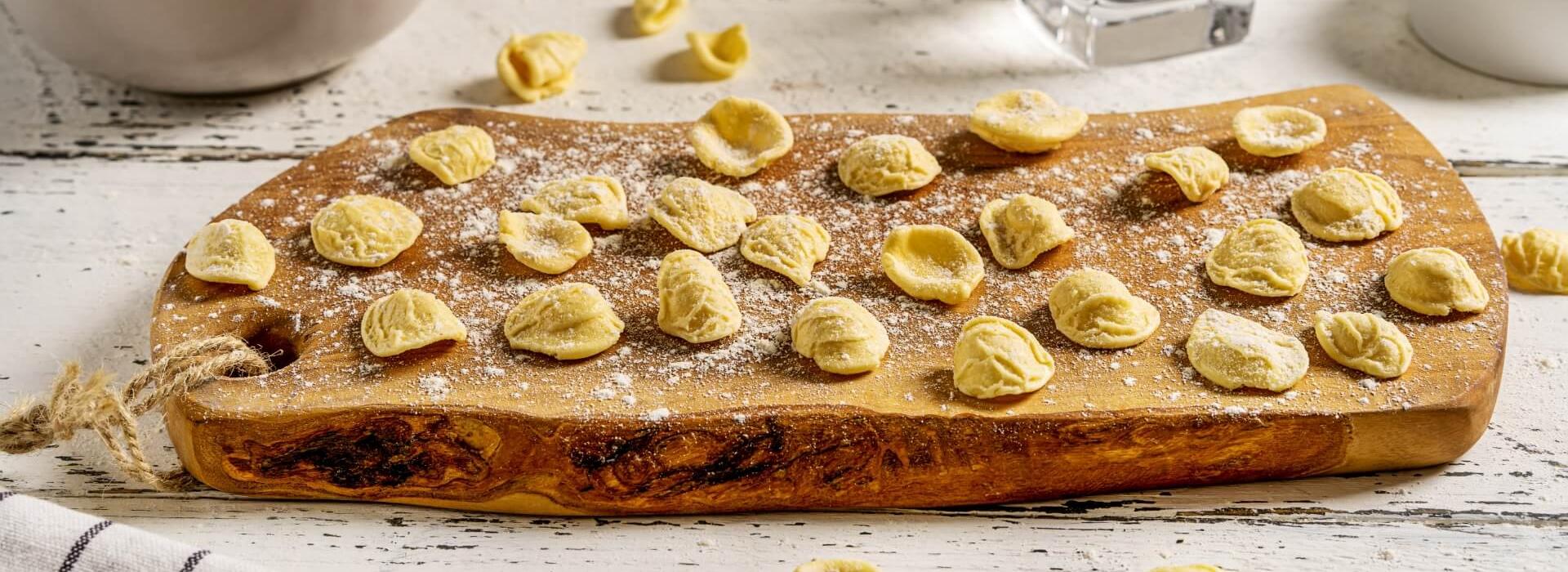 Orecchiette fatte a mano su tagliere di legno, pronte per essere cucinate.