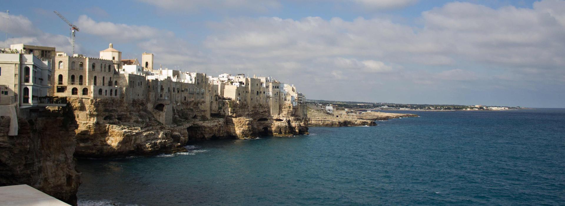 Falaises à couper le souffle avec maisons blanches et mer bleue, ciel partiellement nuageux.