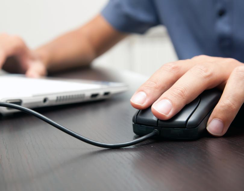 Main sur la souris, travail sur ordinateur, concentration et dévouement.