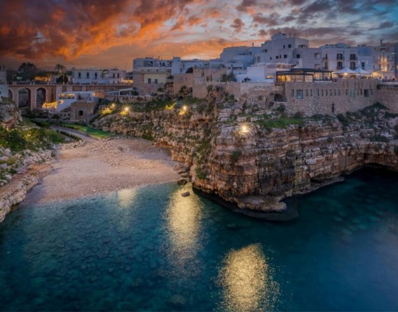 Suggestiva vista costiera al tramonto con edifici storici e mare cristallino.